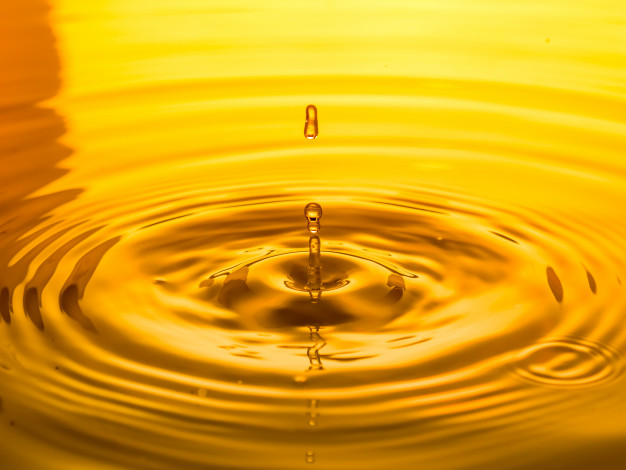 close-up-drop-oil-yellow-background_49683-2045